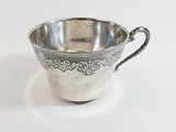 silver plated cup with ornate design on the rim and handle