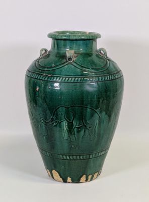 un vase vert sur lequel est représenté un éléphant