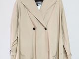 un manteau beige suspendu à un cintre sur un mur blanc