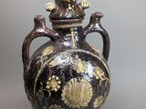 a black and gold vase with a cat on it