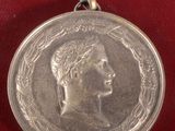une vieille médaille en argent sur laquelle est représenté le visage d'une femme