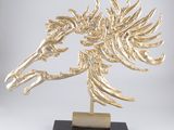 une sculpture représentant une tête de cheval en or, posée sur un socle en marbre noir