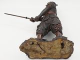 a figurine of a man holding a sword and standing on a rock