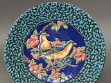 an image of a blue plate with a bird and flowers on it