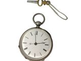 une montre de poche en argent à laquelle est accrochée une chaîne sur le côté