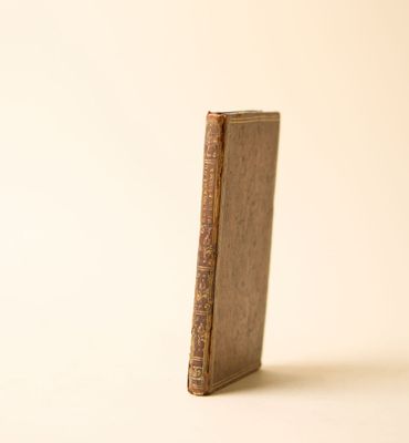 un vieux livre posé sur une table à côté d'un mur blanc