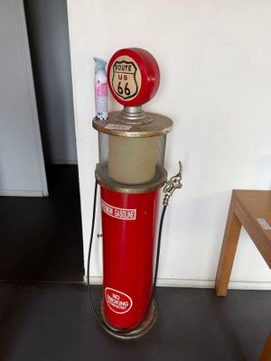 a red gas pump sitting on the floor next to a table