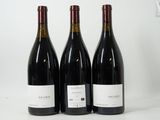 three bottles of red wine are lined up on a white surface