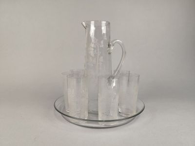 un pichet en verre et quatre verres posés sur une assiette