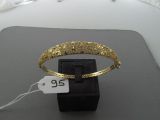 un bracelet en or muni d'une étiquette de prix, posé sur une boîte noire