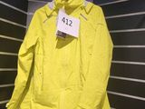 une veste jaune suspendue à un cintre dans une pièce aux murs rayés de noir et blanc