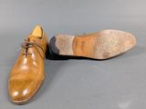 pair of brown leather shoes with laces on a gray surface
