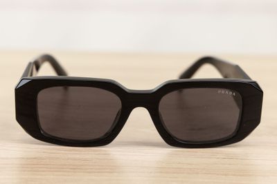 black sunglasses on a wooden table with a white wall in the background