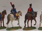 four figurines of soldiers riding horses on a white surface