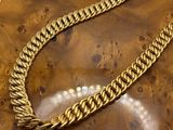 a close up of a gold chain bracelet on a wooden surface