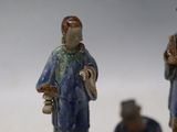 three figurines of people standing on a white surface