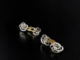 a pair of gold and silver earrings on a black surface