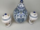 a blue and white vase and two jars on a table