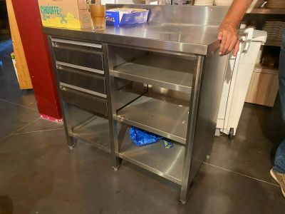 a man standing next to a stainless steel work table