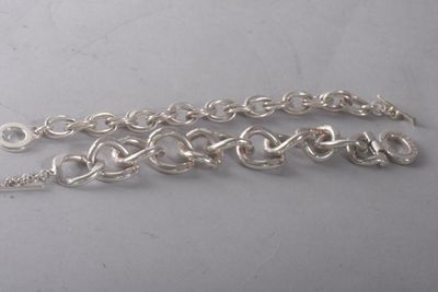 un gros plan d'un bracelet à chaîne en argent posé sur une table