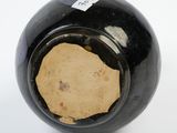 a black vase on a white surface with a tag on it