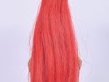 a red doll with long hair on a white table