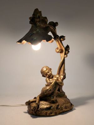 bronze statue of a boy holding a lamp with a bird on it ' s arm