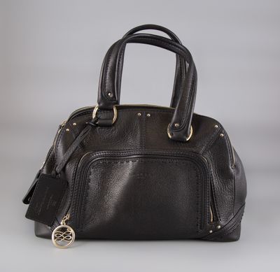 a black leather handbag with gold hardware on a grey background