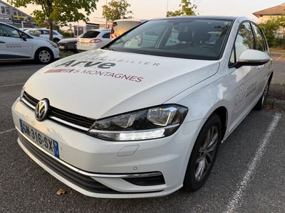 La voiture blanche est garée sur le parking, à côté d'autres voitures.
