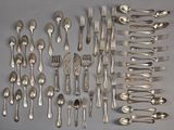 a lot of silver spoons and forks laid out on the table