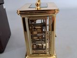 a small gold clock sitting on a table next to a camera