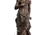 bronze statue of a woman holding a bird on a pedestal