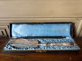 un service d'argenterie dans un coffret posé sur une table en bois