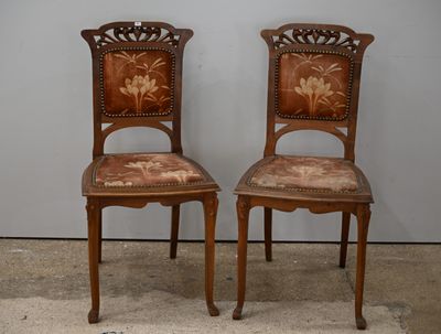 deux chaises en bois ornées de motifs floraux, adossées à un mur gris