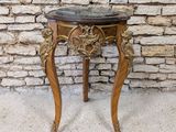 a wooden table with a marble top on a stone floor