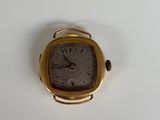 a small gold watch sitting on a white surface