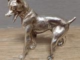 figurine de chien en argent posée sur une table en bois, sur fond gris