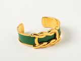 a close up of a gold and green bracelet on a white surface