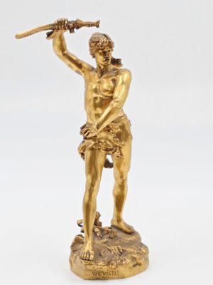 une figurine antique en bronze représentant un homme tenant une batte de baseball