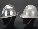 pair of silver hard hats on mannequin heads against a black background