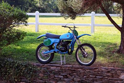 a blue dirt bike parked on the side of a stone wall