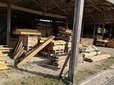 many pieces of wood stacked on the ground outside of a building