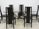 a glass table and chairs in a room with a white wall