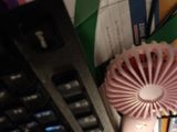 a pink fan sitting on top of a desk next to a keyboard