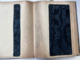 un livre ouvert, avec une couverture noire, posé sur une table blanche