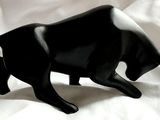 une figurine représentant un taureau noir, posée sur un drap blanc