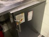 a small silver refrigerator in a kitchen with a coffee maker