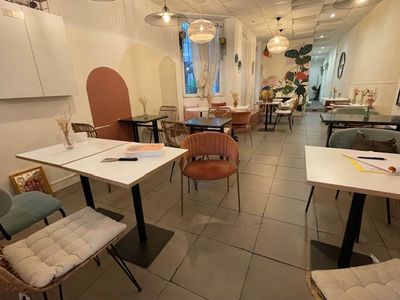 tables and chairs in a room with white walls and a tiled floor