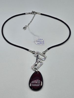 a close up of a necklace on a white surface with a tag