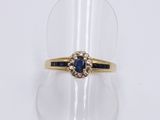 a close up of a gold ring with a sapphire and diamonds